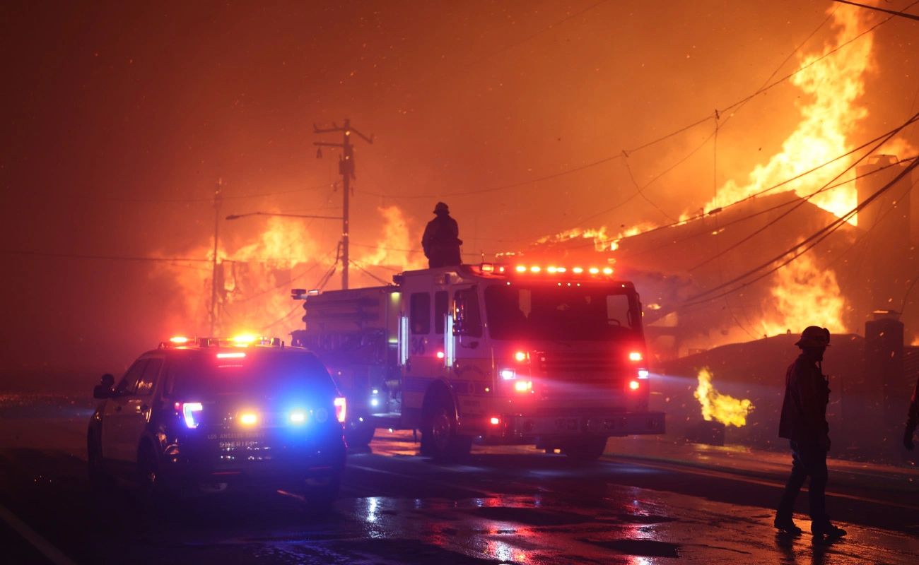 Firefighters battling a wildfire with emergency vehicles